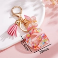 Dettaglio portachiavi lettera G in resina rosa con paillettes a cuore e nappa chic - Rosa G