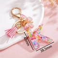 Dettaglio del portachiavi lettera K in resina con paillettes rosa e nappa decorativa - Rosa K