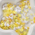 Macro shot of yellow and white acrylic DIY beads in floral shapes on a heart ceramic tray - Yellow Series