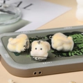 Detailed view of three yellow flocked rabbit charms with silver rings on a tray - Yellow Rabbit