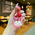 Gros plan du porte-clés renard en acrylique rose avec clochette rouge tenu à la main - Style Mousqueton / Rouge Perle de Bulle Noctilucente Renard