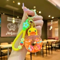 Détail du porte-clés canard jaune avec anneau donut, liquide pailleté et lanière à fleurs - Beignet Phosphorescent À La Vitamine C « Petit Canard Jaune » En Forme De Corde À La Fraise