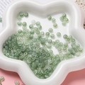 Détail macro de perles d'abaque en verre vert 3x6mm dans un plat en étoile blanche - Perle Rondelle en Verre (AC4486) / Pack de 100 / Vert Foncé / 3*6.5mm