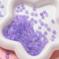 Gros plan de perles en verre violet translucide dans un plateau en étoile pour bijoux - Perle Rondelle en Verre (AC4486) / Pack de 100 / Violet / 3*6.5mm