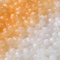 Makroaufnahme von Harzperlen mit Katzenaugeneffekt und Farbverlauf für DIY-Schmuck - Weiß zu Orange
