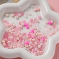 Détail macro de perles de verre 3x6mm roses et blanches dans un plat en céramique blanc - Série Rose