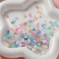 Gros plan de perles d'abaque en verre macaron de 3x6mm sur un plateau en céramique - Transparent Mélangé