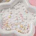 Détail macro de perles en verre pastel 3x6mm pour bijoux DIY dans un plateau étoile - Blanc