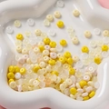 Vue détaillée de perles de verre pastel 3x6mm dans un plateau en céramique pour bijoux DIY - Série Jaune