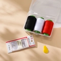 Detail of portable sewing kit featuring three thread spools, needles, and a yellow threader - Black White Red