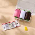 Detail of portable sewing kit with 3 colored thread spools, needles, and ladybug threader - Pink White Coffee