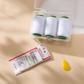 Detail of sewing kit with white thread spools, needles, and a yellow needle threader - White