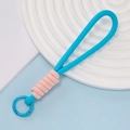 Porte-clés en corde tressée rose et bleu avec mousqueton rond sur un plateau déco - Style 08
