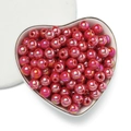Dettaglio macro di perle acriliche rosa acceso con finitura AB in vassoio a cuore - Rosso