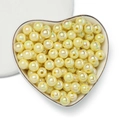 Vista macro di perle tonde in acrilico crema con finitura AB in piatto a cuore - Giallo