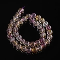 Macro shot of natural ametrine round beads with purple and yellow hues on black background - Purple Yellow Ghost