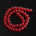 Macro shot of red translucent Czech glass beads spirally arranged on black mirror - Red