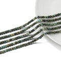 Dettaglio macro di perle quadrate sfaccettate in pietra naturale da 3mm in verde e grigio - Pietra di pino africano