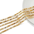 Dettaglio macro di perline a cubo in pietra naturale gialla da 3 mm per gioielli fai da te - Conchiglia Gialla