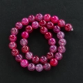 Macro-opname van rozerode agaatkralen met drakenadertextuur voor DIY-sieraden - Rood
