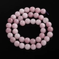 Macro-opname van doorschijnende roze ronde agaat kralen op een glanzende zwarte spiegel - 6,5 mm (ca. 57 kralen/streng) / Kunziet