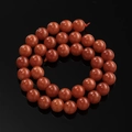 Macro-opname van gepolijste oranje drakenader agaat kralen in een cirkel op zwarte ondergrond - 6,5 mm (ca. 57 kralen/streng) / Rood Koraal
