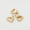 Tre fermagli a moschettone dorati a forma di cuore per gioielli fai-da-te su sfondo grigio - Chiusura Moschettone Cuore Oro 18K