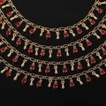 Vue macro d'une chaîne coeur dorée avec cristaux rouges et breloques en métal - 1m / KC Or - Zircon Goutte d'Eau