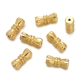 Close-up of golden dumbbell-shaped jewelry screw clasps with detailed radial engravings - Gold