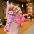 Détail d'un porte-clés hélicoptère rose avec paillettes, clochette dorée et lanière cœur - Rouge
