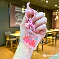Detailed hand-held view of pink liquid handbag keychain with red beads and flower sequins - Lobster Clasp Style / Pink