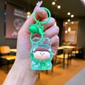 Detail of green resin liquid quicksand keychain with glitter and a small bell charm - Color Hardware Style / Green