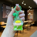 Gros plan sur un porte-clés dessin animé avec sable mouvant liquide et paillettes vertes - Style Mousqueton / Matériel Vert Flash Lumineux Sœur Fruits