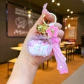 Detail of Sakura luggage charm with pink cherry blossom pendant and golden bell keyring - Quicksand TV / Sakura Strap (White)