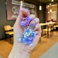 Vue détaillée d'un porte-clés ours en résine violette avec paillettes et clochette - Violet