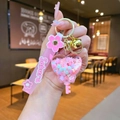 Macro view of a pink sakura liquid sand keychain with glitters and a golden bell charm - Sakura Rope - Pink