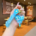 Detail of blue heart-shaped oil-filled keychain with Sakura strap and golden bell charm - Sakura Rope - Blue