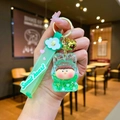 Detailed macro of green liquid sand Lilith keychain with gold glitter and floral charms - Leather Cord Style / Green