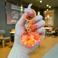 Nahaufnahme vom orangefarbenen Herz-Lollipop-Schlüsselanhänger mit Flügeln und Glocke - Orange