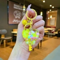Close-up of heart-shaped liquid quicksand bottle keychain with colorful beads and bell - Yellow