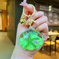 Detail of green acrylic shell keychain with liquid glitter sand and gold metal bell - Green Shell With Golden Hardware