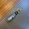 Close-up of translucent grey acrylic keychain with Bubble script and golden metal ring - Black
