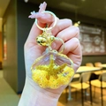 Detail of shell keychain with yellow sand and golden starfish in a hand-held macro shot - Yellow Shell With Golden Hardware