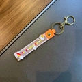 Detail of orange PVC strap with The Sunshine Unicorn text and golden metal keychain clip - Unicorn Rainbow Strap / Orange