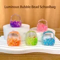 Pendentifs sac à dos lumineux avec perles colorées sur supports d'exposition blancs - Sac d’école