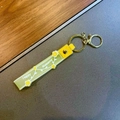 Macro shot of yellow silicone lanyard keychain with Happy Moments print and golden ring - Yellow
