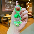 Vue en main d'un porte-clés patte de chat en acrylique avec paillettes et clochette - Style Mousqueton / Vert (Mini Patte de Chat Flocon)