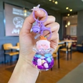 Détail d'un porte-clés cochon rose avec clochette violette et bouteille de sable mouvant - Style Matériel Coloré / Violet