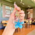 Detail of blue starfish liquid sand flower keychain with golden lobster clasp and bell - Pendant Only (Without Chain) / Blue Flower With Golden Hardware