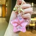 Acrylic star keychain with pink moving sand, seashell and golden bell attachment - Pink Star With Golden Hardware